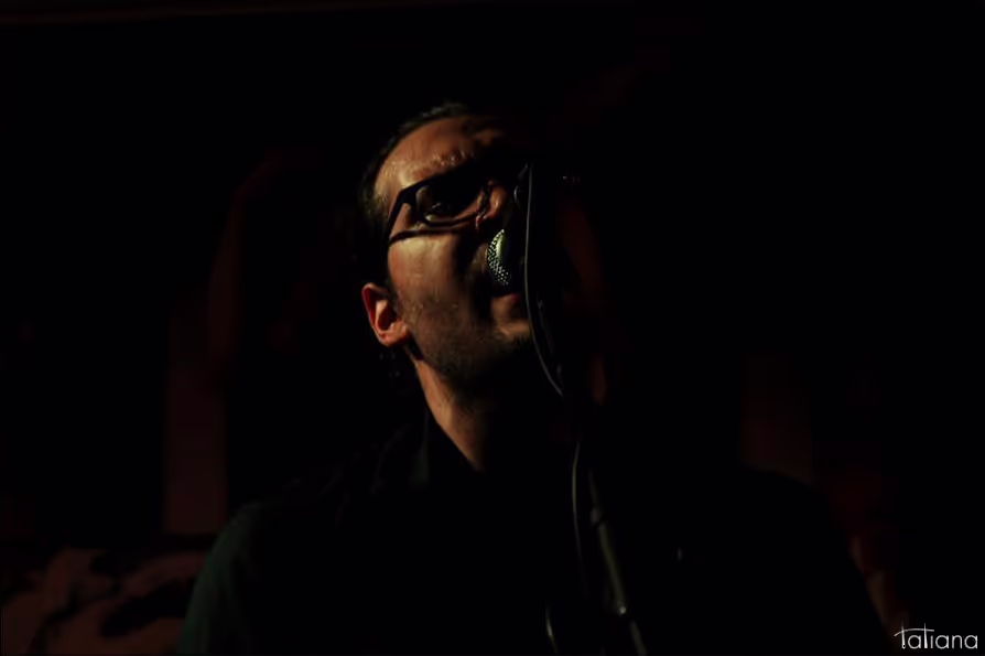 Petros passionately singing into the microphone on stage, delivering a captivating performance.